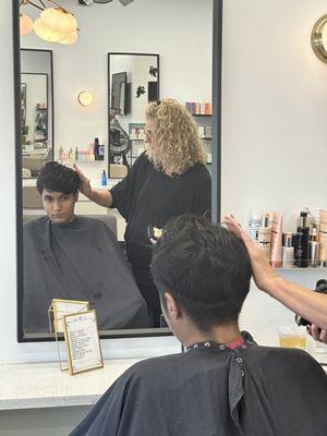 Demetrios receiving hair cut from Lucinda.