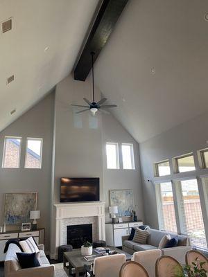 Large wooden beam installation across a vaulted living room ceiling.