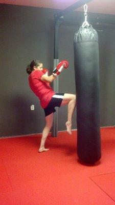 Jenny throwing a Muay Thai knee on a heavy bag.