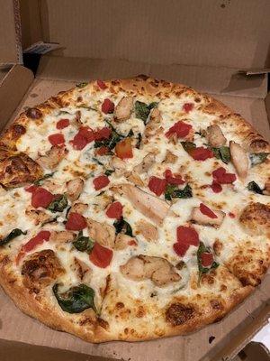 Large chicken, spinach, and tomato pizza with white garlic sauce.