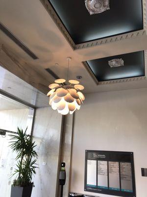 More modern artichoke-type downward lamps throughout the lobby. The directory can be seen on the far wall.