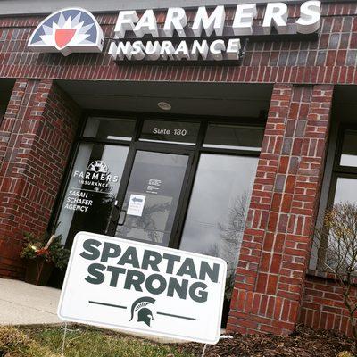 Photo of the Sarah Schafer Agency - Lansing Office's facade with a "Spartan Strong" sign in the front lawn of the building