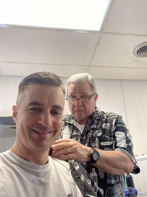 A handsome guy getting a haircut from the owner.