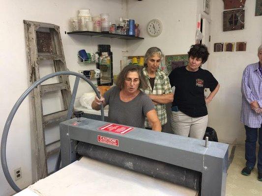 Demonstrating how to use a slab roller in a workshop