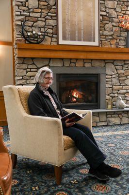 A resident reads by the fire in our Great Room.