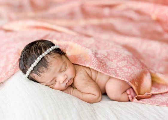 Newborn baby girl sleeping with mother's pink saree.