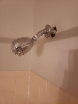 The pipe leading the water to the shower nozzle is coming out of the wall.