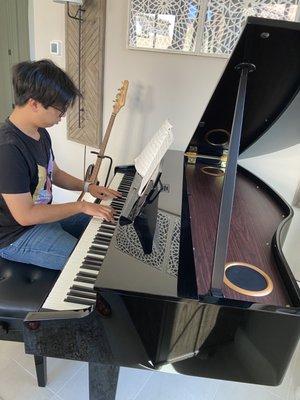 My son enjoying the first few moments with our new Roland baby grand.