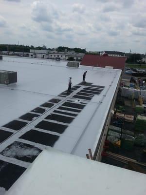 Astec roof coating being applied to a  black  rubber roof.  Will now be seamless and Hassal free.