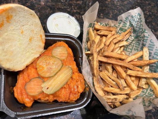 Chicken sandwich tossed in wing sauce and a large order of fries.