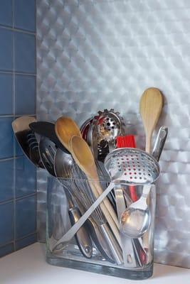 Glass tiles and quartz countertop next to a metal laminate pantry wall adds interest and easy maintenance for this kitchen.