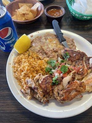 This is the chicken plate with rice and fried beans with a Pepsi