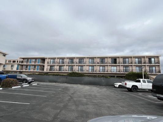 The hotel property with rooms near the ocean and behind another hotel parking lot.