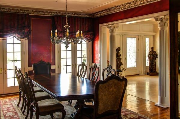 Stencil designs over wine colored walls with a faux metal plaster cornice and chandelier topped with an accented ceiling.