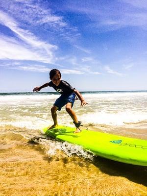 Liam shredding, learning and smiling during his first lesson with the Surf City Surf School.