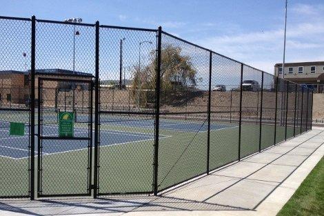 Tennis court with black chain link fencing.