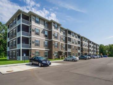 an apartment building with cars parked in a parking lot