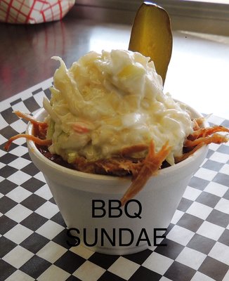 BBQ Sundae, starts with Cowboy Beans topped with Pulled Pork, coleslaw and pickle spear.