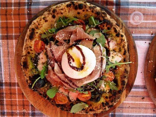 Fired truffle pizza with fresh basil, cheese, olive oil, and a round of mozzarella drizzled with aged balsamic vinegar.