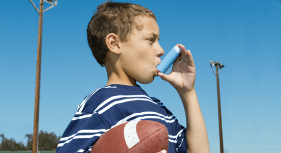 A boy with asthma, who is using his inhaler