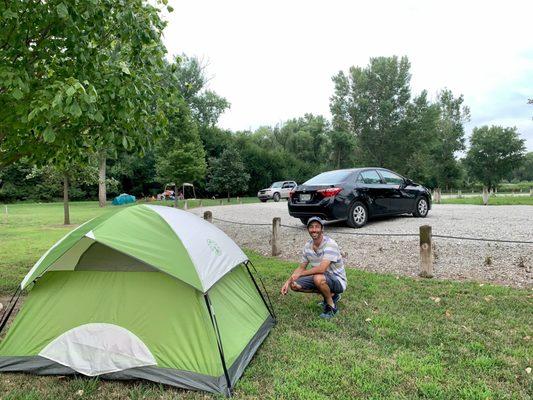 Here my tent set up on grass with my car nearby and other campers in the background spaced far away from my site.