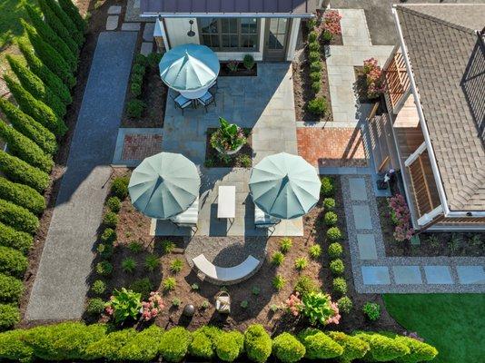 You can fit a lot into a relatively small space! bluestone patio with brick accents, cornhole court, herb garden and lush planting beds.