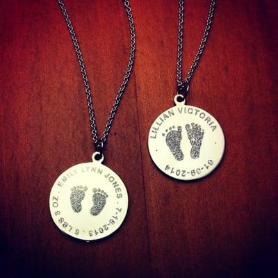 Custom engraved sterling silver disc charm necklaces with actual baby footprints and birth details from a birth certificate.