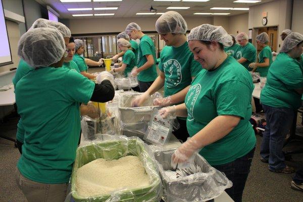 Students volunteer their time to projects such as making meal packets to help stop hunger.