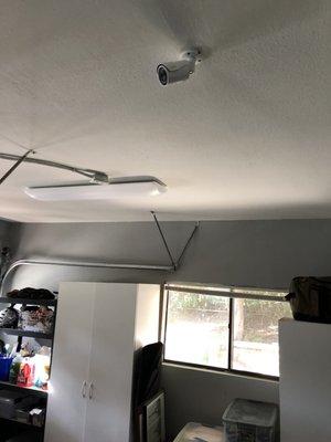 Clean camera mount in garage ceiling. Cables are routed through crawl space above.