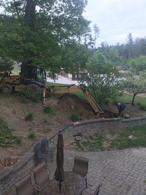 Backhoe just about kissing the retaining wall.