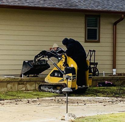 Mini skid steer laying the river rock precisely. No damage to any surrounding