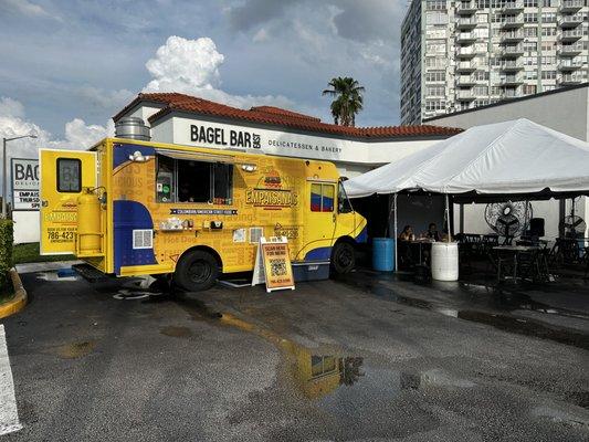 We are located in the parking lot of bagel bar east. Tent and seating are provided.