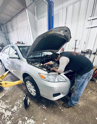 An internal engine repair is being carried out by an employee at Anchor Auto Service.