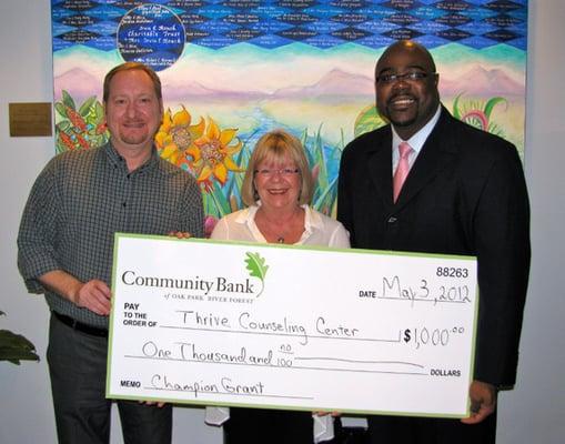 CEO Nina Allen and Christopher Fox accept the Champion Grant from Bernard Headley of Community Bank of OPRF.