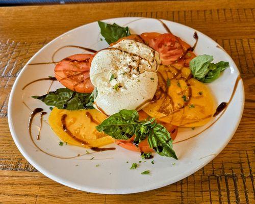 Tomato caprese salad with burrata, heirloom tomato slices, and balsalmic glaze drizzle.