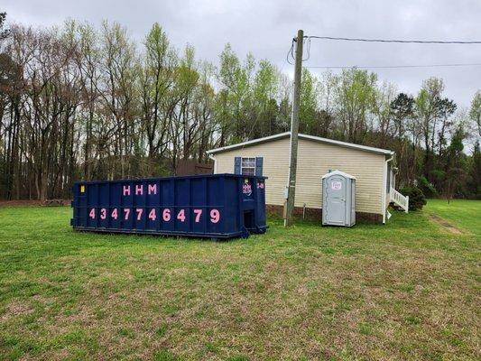 Job site with a portable toilet and a roll off dumpster