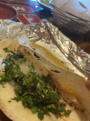 Chicken taco topped with cilantro, onion, & cheese