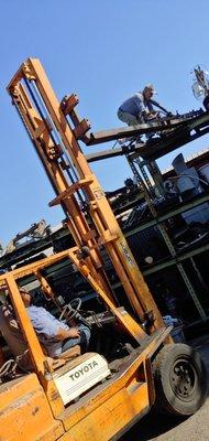 Circus act, 72 year old paratrooper climbs forklift and walks across fork like a tight rope.