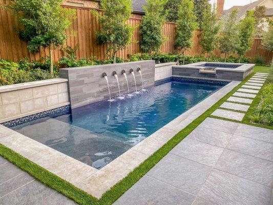 Backyard renovation with a pool, hardscape, turf and a waterfall