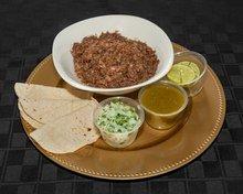 Deliciosa barbacoa de res cocinada a vapor y acompanada con Cebolla y cilantro y su salsa de tomatillo.