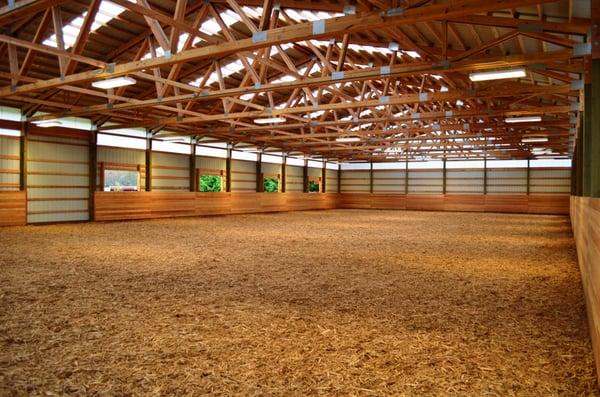 Covered horse arena interior shot. Includes tongue and groove kick wall and ample lighting.