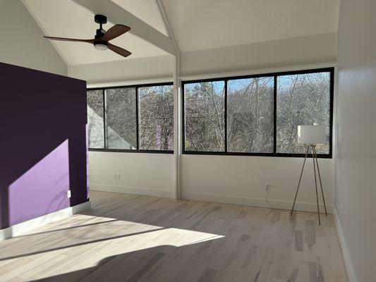 A freshly renovated primary bedroom with new hardwood floors and ceiling fan