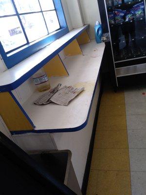 Dirty counter w trash n bottle of urine.