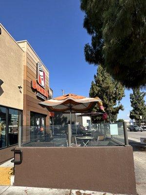 Outdoor Patio with tables, chairs & umbrellas in front of the entrance @ Glenoaks Blvd Dunkin' Donuts in Burbank CA.