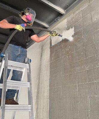 Easily removing old paint off a warehouse interior wall.