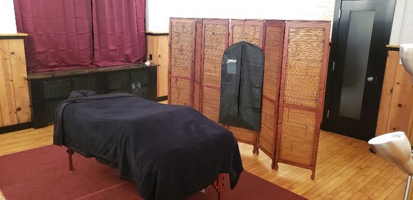 Treatment space with massage table and room dividers.