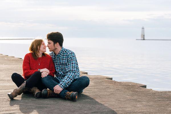 A couple sitting on the pier in Elberta, MI during an engagement session.