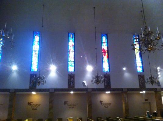 Stained glass windows of saints, Stations of the Cross, and Bible quotes.