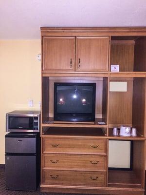 Large entertainment center, along with a microwave a separate fridge and freezer.