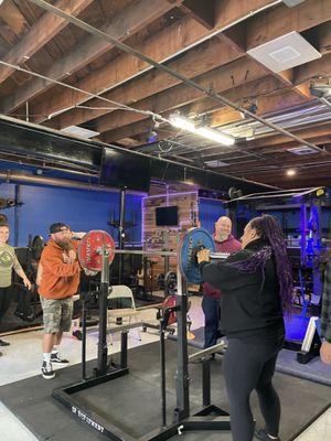 Competition squat rack and gym members setting up